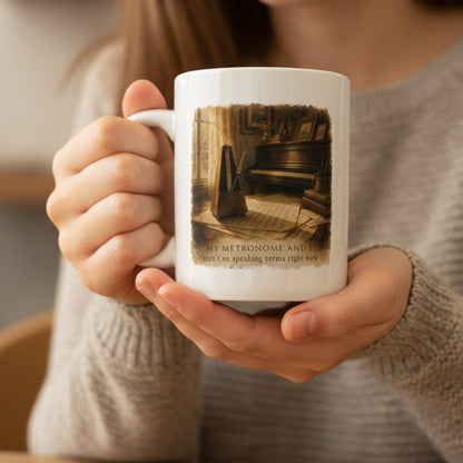 Person holding the A Question of Time piano mug, showing the vintage piano and metronome artwork while enjoying a warm drink.