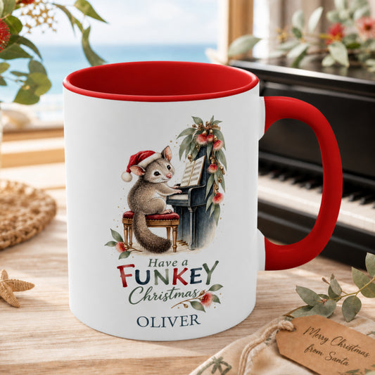 Personalised possum piano Christmas mug with red handle beside a piano